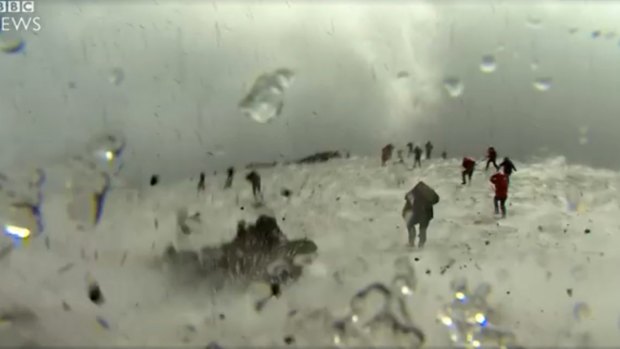 Tourists in the snow running away from the explosion on Mount Etna .