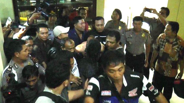 Handcuffed, David Taylor arrives at Denpasar police station on Friday.