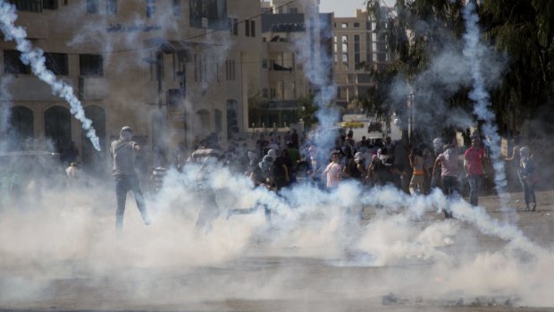 Palestinian protesters run for cover after Israeli soldiers fire tear gas during clashes near Ramallah on Saturday.