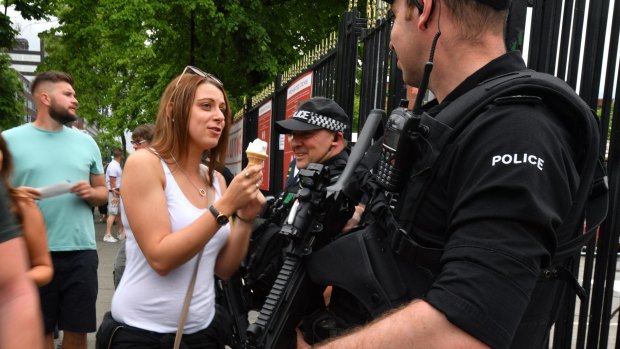 A woman offers her ice cream to a police officer as armed police patrol around Old Trafford Cricket Ground ahead of a Courteeners concert ahead of the One Love benefit set to take place on Sunday night.