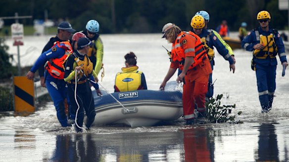 A woman and her baby being brought across the flooded road.
