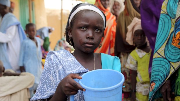 A girl drinks water as women queue for blankets and food given out by Nigerien soldiers in March. 