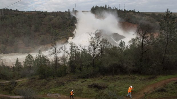 Crews work to move two electric transmission line towers as a precaution should the Oroville Dam emergency spillway need to be used.