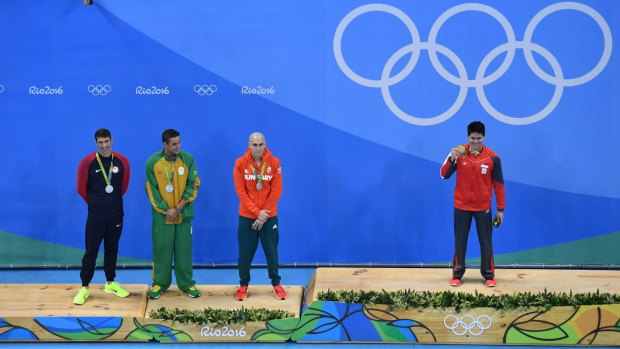 Joint silver medalists, Michael Phelps, Chad  Le Clos and Laszlo Cseh watch as Joseph Schooling shows off his gold medal.