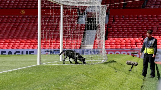 A police sniffer dog and handler on the pitch at Old Trafford stadium after the final match of the season between Manchester United and AFC Bournemouth was abandoned. 