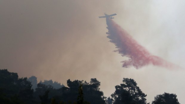 A firefighting aircraft drops fire retardant material in efforts to contain a huge forest fire that continues to rage out of control in the mountainous areas southwest of Cyprus' capital Nicosia.