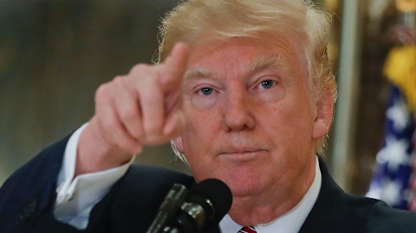 US President Donald Trump points to members of the media as he answers questions in the lobby of Trump Tower in New York.