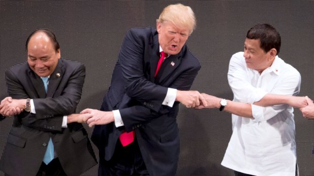 US President Donald Trump, center, reacts as he does the "ASEAN-way handshake" with Vietnamese President Tran Dai Quang, left, and Philippines President Rodrigo Duterte during the opening ceremony of the ASEAN summit in Manila, Philippines. 