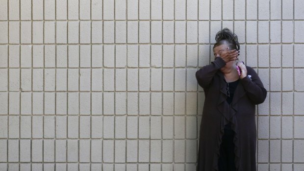 A woman wipes her tears at a community centre where family members are gathering to pick up survivors.