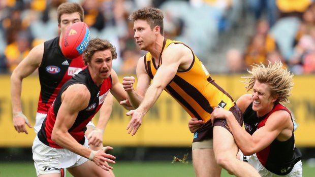 Liam Shiels handballs as Bomber Dyson Heppell tries to hang on.