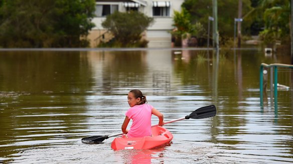 Maleah Jones, 8 years old, canoes up flooded Bright street to her home in Lismore.