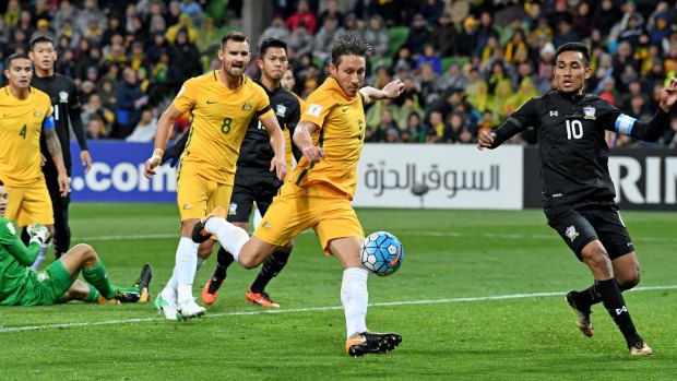 Patience please: Mark Milligan of the Socceroos strikes the ball but fails to break through.