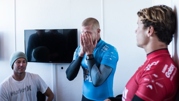 Mick Fanning holds his head in his hands in disbelief after being attacked by a shark during the final of the JBay Open while fellow finalist Julian Wilson (red) looks on.