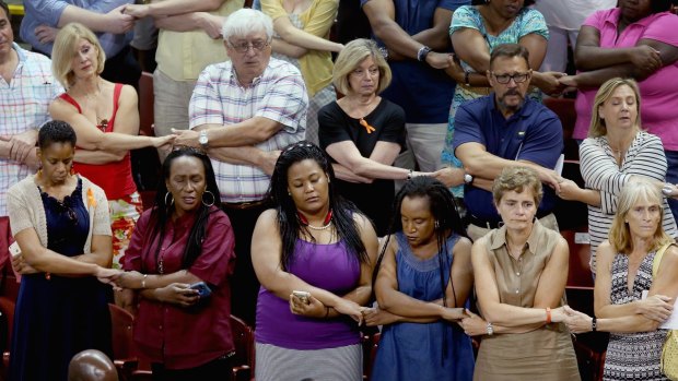 Thousands of people hold hands and sing We Shall Overcome during a prayer vigil for the nine victims of the Emanuel AME Church shooting at the College of Charleston TD Arena on June 19. 