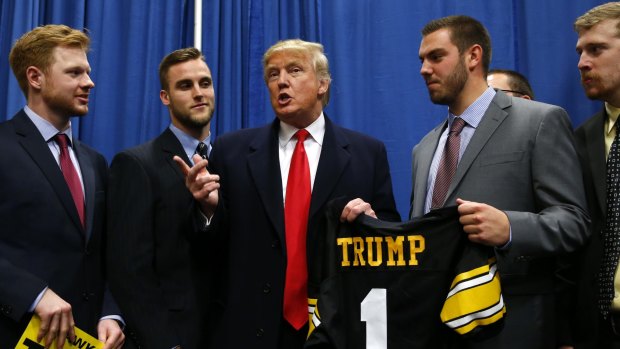 Republican presidential candidate Donald Trump speaks with University of Iowa football players before a campaign event at the University of Iowa.