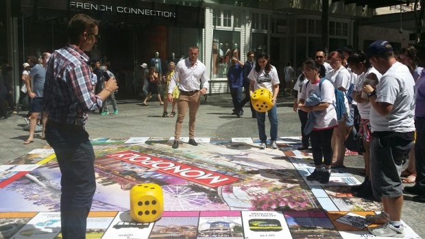 People play the new Brisbane version of Monopoly in Queen Street Mall.