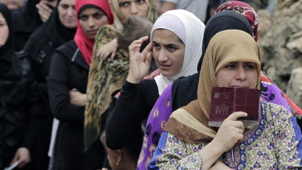 Syrian women wait in line to receive aid from an Islamic relief agency at a refugee camp in the town of Ketermaya, north of the port city of Sidon, Lebanon. 