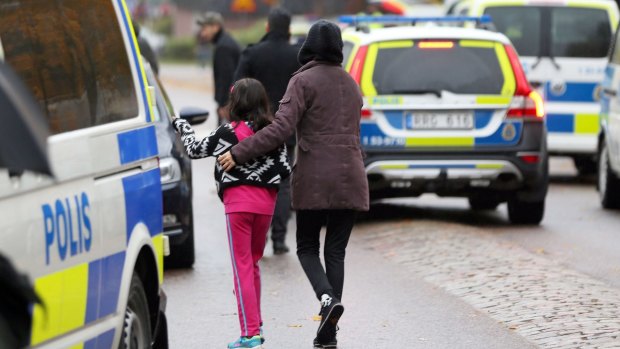 Students and parents leave the scene of a sword attack by a masked man at the Kronan school in Trollhattan, Sweden.