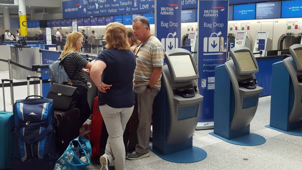 Passengers stand at the British Airways check-in desk after the airport suffered an IT systems failure.