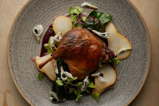 Confit duck leg with pears and broad bean flowers.