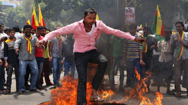 An activist jumps over a burning effigy during protests in Bangalore this week that forced many large Indian and foreign companies to close their doors.