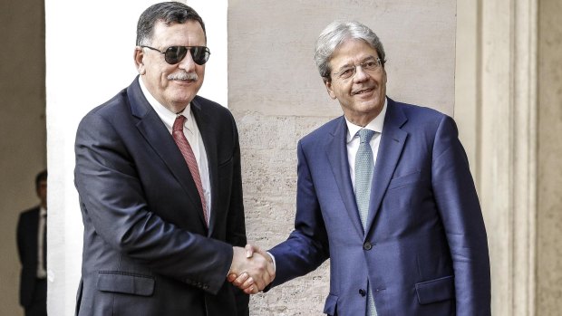 Italian Premier Paolo Gentiloni, right, welcomes Libyan Prime Minister Fayez al-Sarraj in the courtyard of Chigi Palace in Rome.