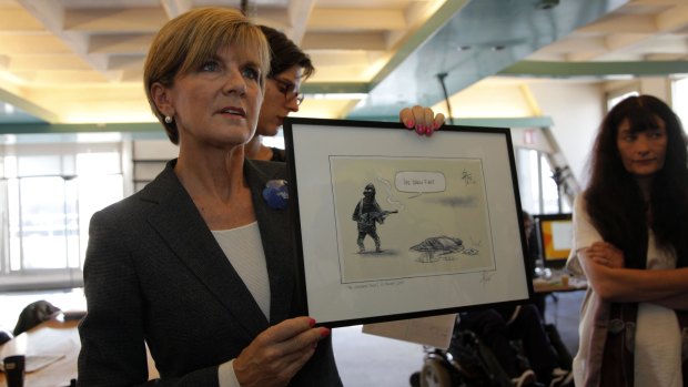 Julie Bishop shows off the cartoon before presenting it to the survivors of the <i>Charlie Hebdo</i> attack.