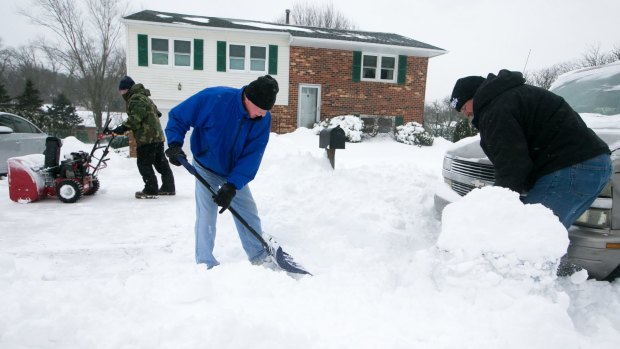 Andy Mathe, left, helps his neighbor Charlie Faville, dig out from a heavy snowfall.