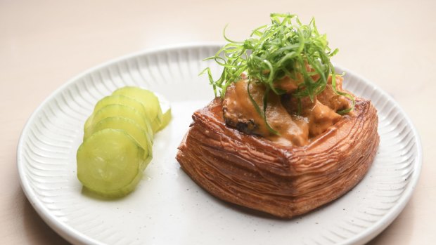 Lune croissant loaded with butter chicken and served with pickles.