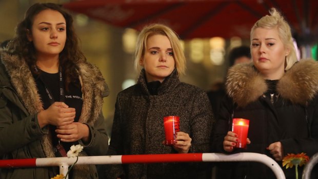 Young women hold candles at a makeshift memorial at the scene of the Berlin Christmas market attack.