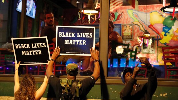 Protesters hold up signs during protests which turned ugly.