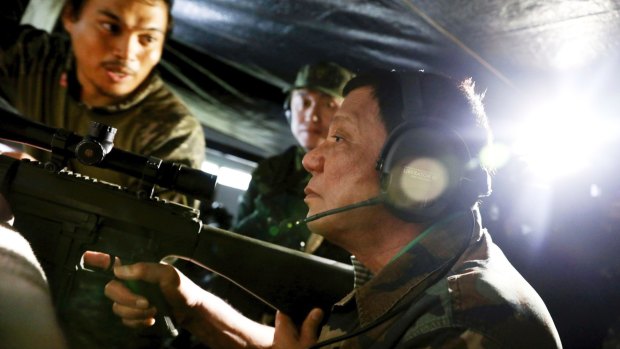 President Rodrigo Duterte holds an assault rifle during a visit to Marawi in southern Philippines.