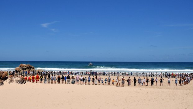People gather on Lighthouse Beach near Port Macquarie to show support for the family of an 11-year-old boy from the ACT who was swept out to sea.