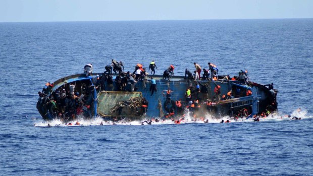 People jump off a boat moments before it overturns off the Libyan coast, in May.