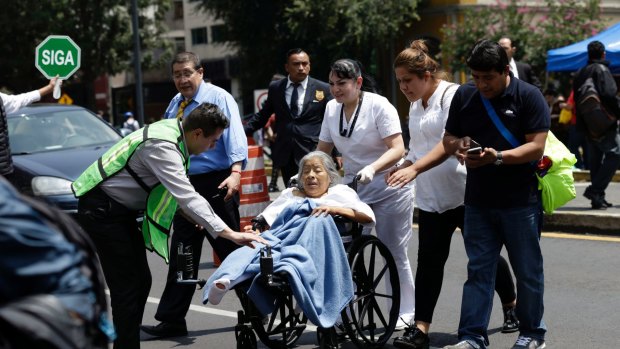 A woman in a wheelchair is evacuated from a clinic in Mexico City.