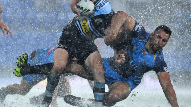 Big wet: Chad Townsend is tackled by Ryan James in atrocious conditions at CBUS Stadium on the Gold Coast.