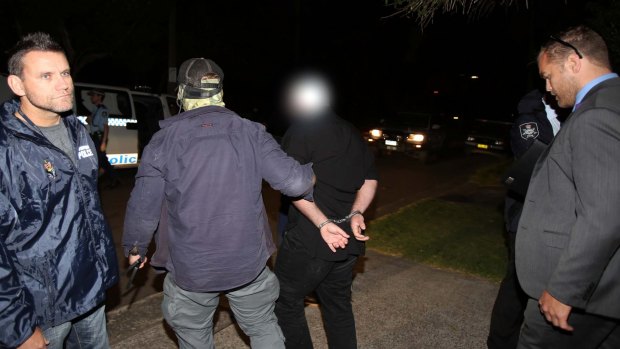 Terrorism arrests: A man is taken away in handcuffs in Marsfield.