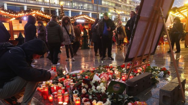 A visitor lays a candle at a makeshift memorial inside the reopened Breitscheidplatz Christmas market.