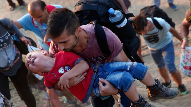 A young Syrian boy cries as his father carries him up a steep hill as they walk to a border crossing on the Greek and Macedonian border near Idomeni, Greece.