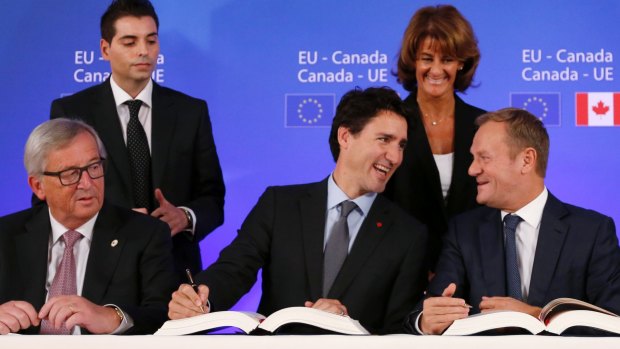 Canadian Prime Minister Justin Trudeau, centre, signs the trade deal with European Commission president Jean-Claude Juncker, left, and European Council president Donald Tusk, right.