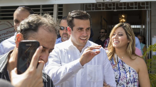 Ricardo Rossello, governor of Puerto Rico, centre, and his wife Beatriz Isabel Areizaga, right, greet voters at a polling station on Sunday.