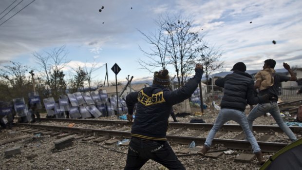 Migrants hurl stones at Macedonian policemen during clashes at the Greek-Macedonian border,.
