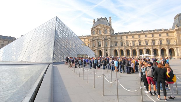 Visitors queue to enter the Louvre museum in Paris.