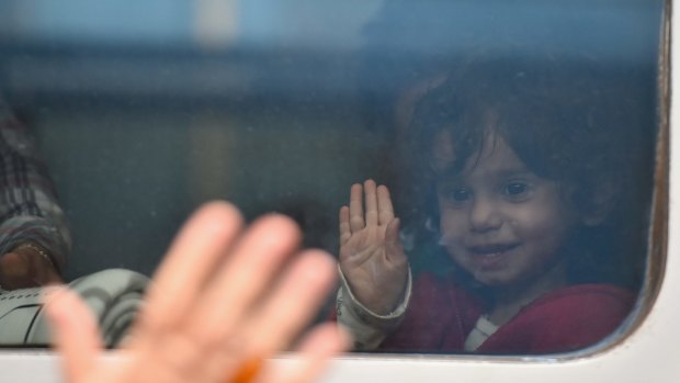 A girl waves from the window of a train leaving for the Austrian border at Keleti railway station in Budapest.