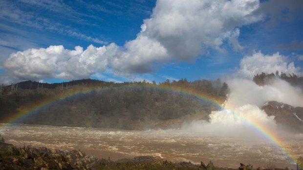 A rainbow over the Feather River as water cascades down the damaged spillway at Oroville Dam .