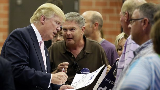 Trump signs autographs after speaking at a rally and picnic in Iowa.