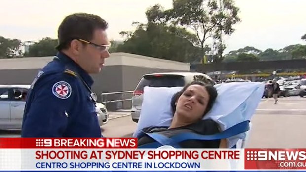 A woman is wheeled away by paramedics after the shooting at Bankstown Central Shopping Centre.
