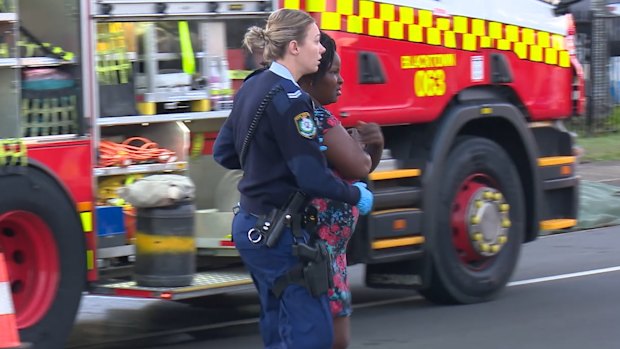 Police help a woman at the scene of the fire.