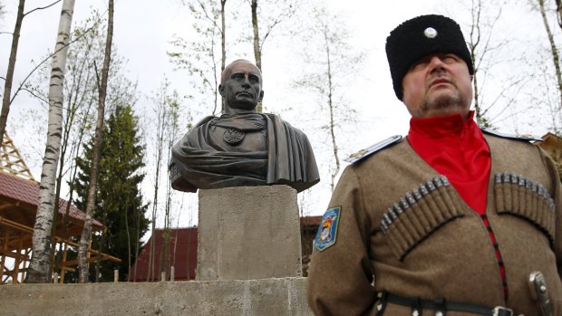 Leader of Orthodox Cossack Union "Irbis" Andrei Polyakov stands next to a bust of Russian President Vladimir Putin which depicts him as a Roman emperor.