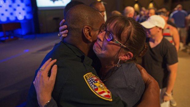 East Baton Rouge Sheriff officer Eddie Guidry is comforted by Terri Carney. Both are members of the Rock Church, which has held a prayer vigil for the officers killed and wounded in Baton Rouge on Sunday.